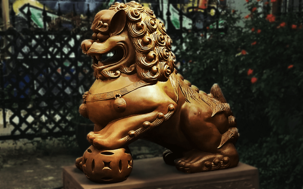 Golden Chinese lion dog with ball under its paw