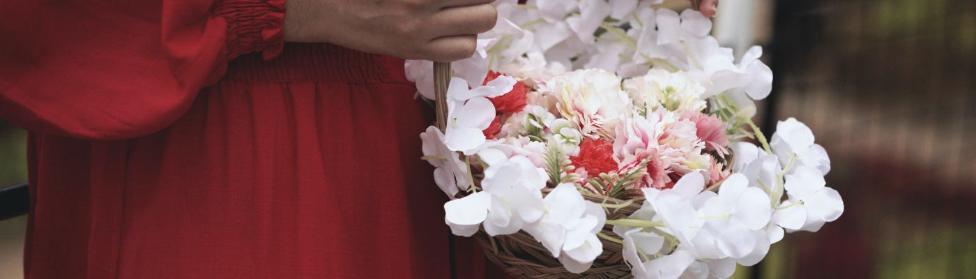 person in a red dress holding a basket of white flowers
